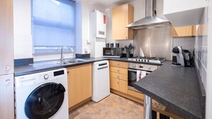 A compact kitchen with a washing machine, a stove, and a microwave.