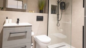 Un baño moderno con ducha de vidrio, inodoro y tocador con cajones.