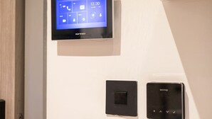 Panel de control montado en la pared con pantalla digital que muestra la hora y la fecha, un interruptor de encendido y un termostato.