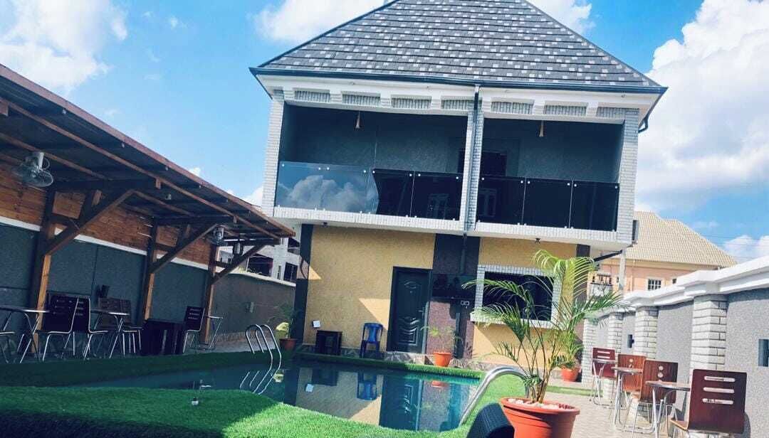 Uma casa de dois andares com piscina na frente.