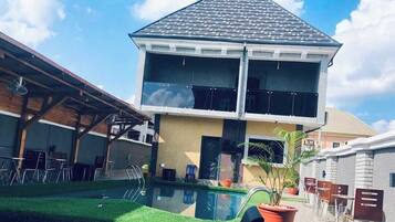 Uma casa de dois andares com piscina na frente.