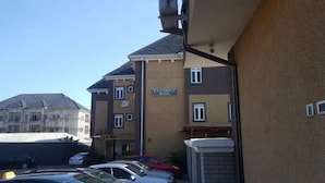 Ein mehrstöckiges Gebäude mit einem Schild, das es als Hotel kennzeichnet. Vor dem Gebäude sind mehrere Autos geparkt und es besitzt ein geneigtes Dach.