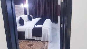 Ein Hotelzimmer mit Bett, Nachttisch, Lampe und einem Vorhangfenster.