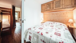 A bedroom with a wooden headboard, a bed with a patterned quilt, a wooden cabinet above the bed, and a nightstand with a lamp.