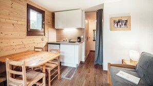 A compact kitchen with wooden cabinetry and a dining area with a wooden table and chairs.