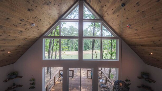 A high-ceilinged room with large windows offering a view of a wooded area. - #1 Passionflower at Lost Forest Cabins (Richards)