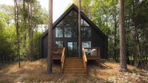 A cabin with a wooden deck and a staircase leading to a bed. - #1 Passionflower at Lost Forest Cabins (Richards)