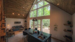 A spacious kitchen with a large island, wooden ceiling, and large windows offering a view of the outdoors. - #6 Turkey Tail at Lost Forest Cabins (Richards)