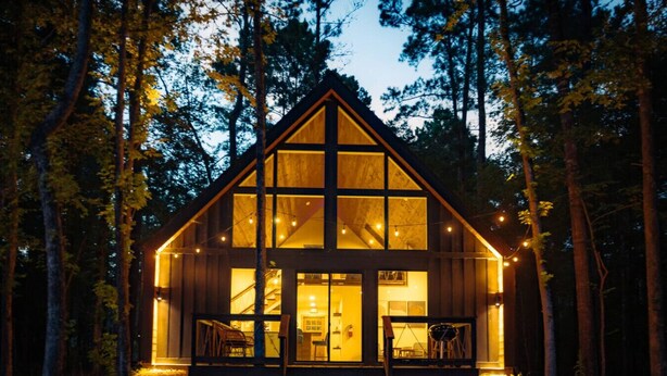 A cabin with a large front window, a staircase leading to the entrance, and a porch with chairs. - #7 Beauty Berry at Lost Forest Cabins (Richards)