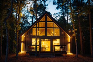 A cabin with a large front window, a staircase leading to the entrance, and a porch with chairs. - #7 Beauty Berry at Lost Forest Cabins (Richards)