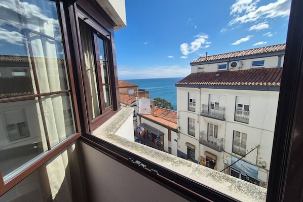 A view from a window overlooking a coastal town with buildings and the sea.