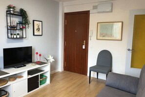 A living room with a flat-screen TV, a grey sofa, a wooden door, and a framed picture on the wall. - 14A11 Apartment with Views in Lastres by R2R (Lastres)