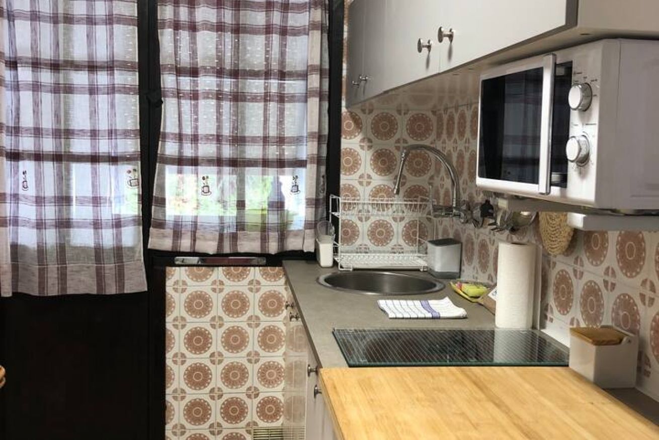 Une cuisine de taille réduite, équipée d’un four à micro-ondes, d’un évier et d’un crédence décorée.