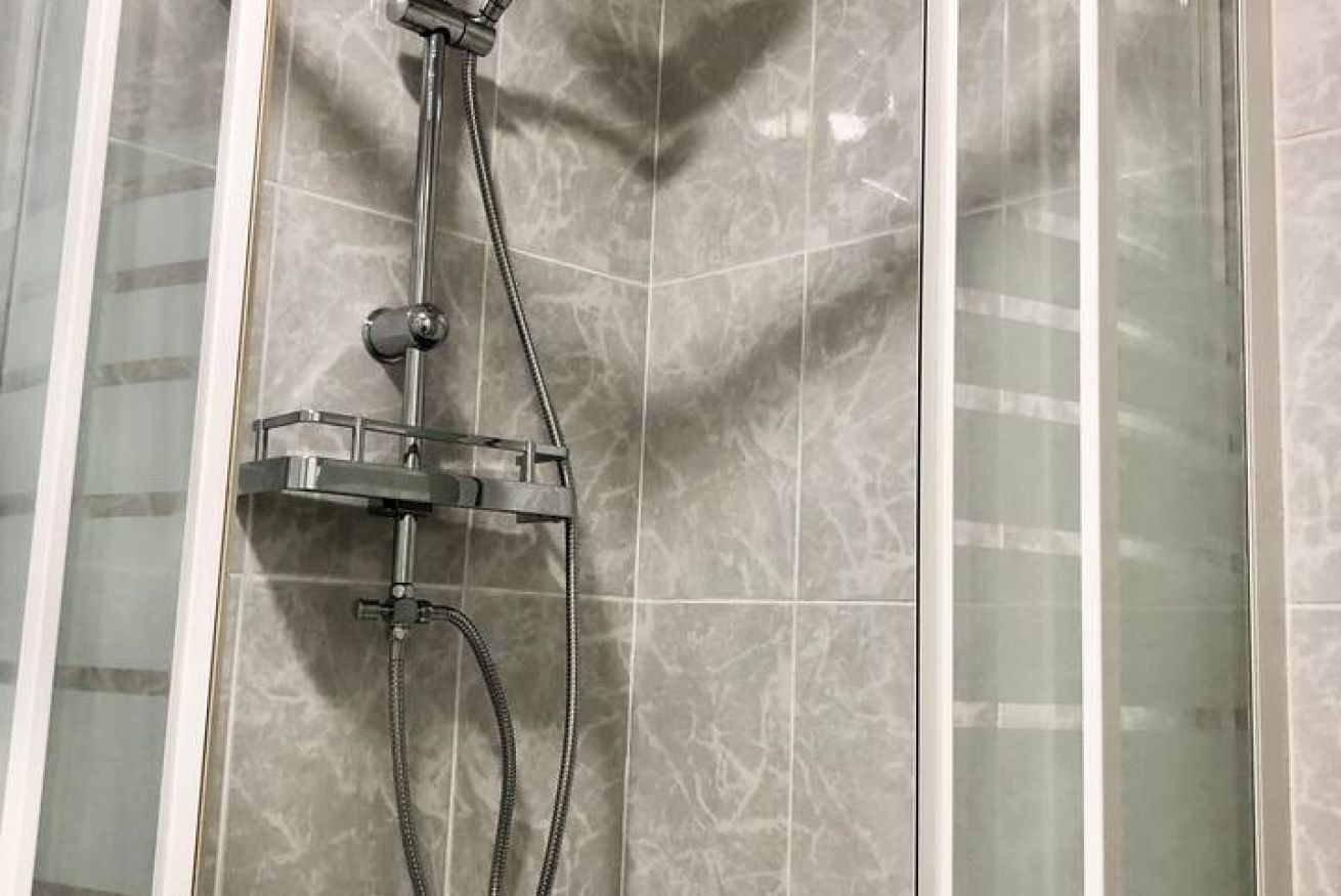 Un box de ducha con ducha de mano y manguera.