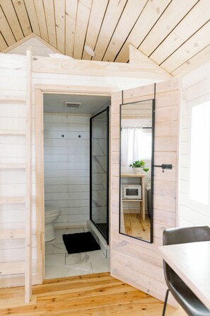 Une salle de bain compacte comprenant une douche, des toilettes et un petit lavabo.