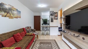 Una sala de estar con sofá, televisión y una obra de arte en la pared.