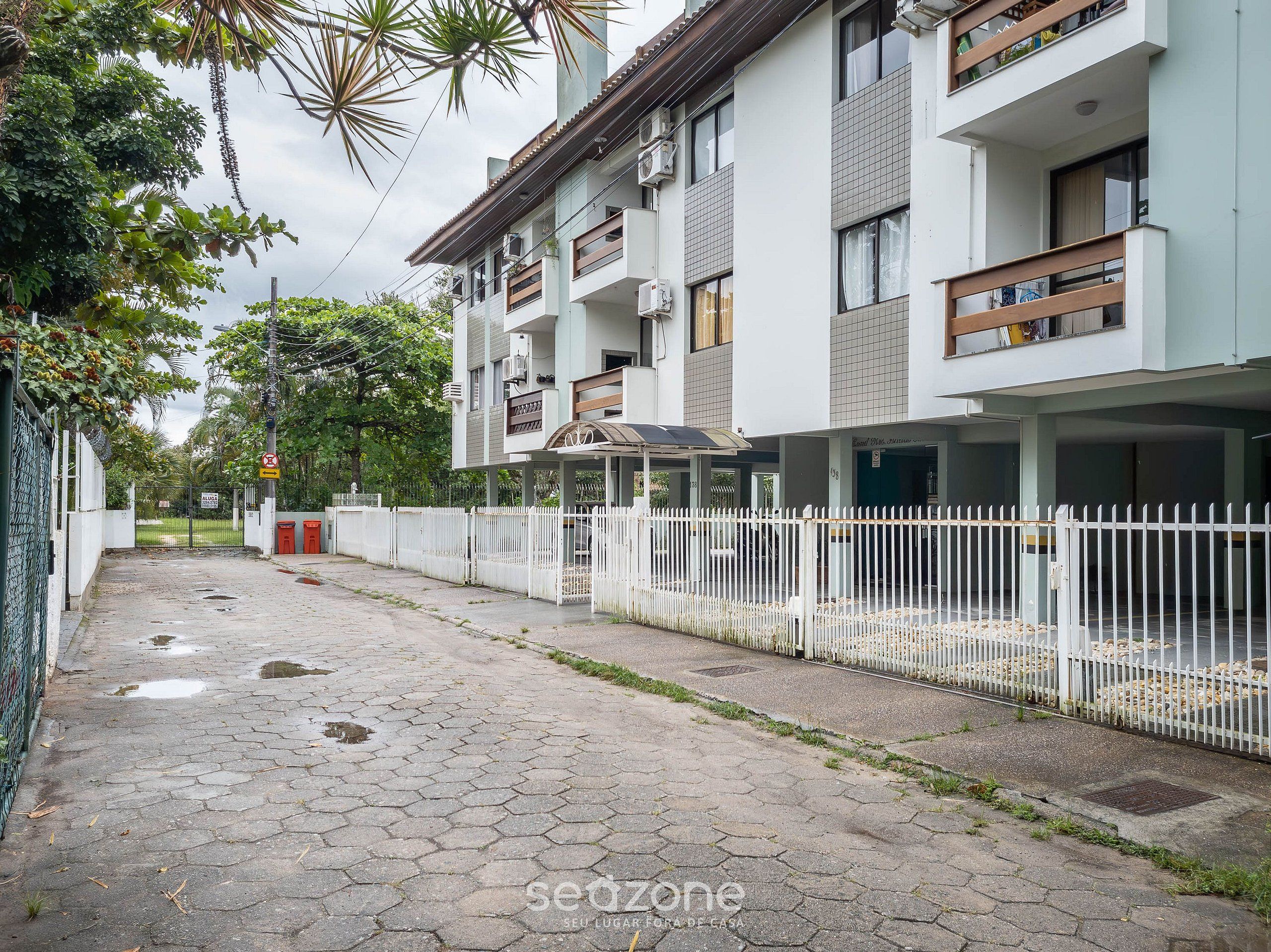 Un edificio residencial con varios balcones, una entrada con portones y un camino pavimentado.
