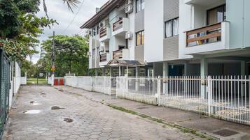 Un edificio residencial con varios balcones, una entrada con portones y un camino pavimentado.