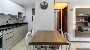 Una cocina moderna con armarios blancos, una mesa de comedor de madera y un reloj en la pared.