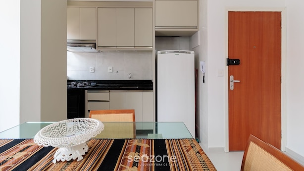 Una cocina compacta con electrodomésticos modernos, una mesa de comedor con un centro de mesa decorativo y una puerta de madera.
