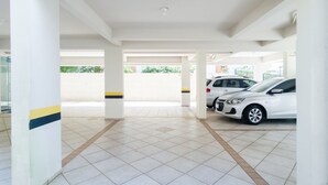 Un estacionamiento interior con pilares blancos, pisos de baldosas y dos coches estacionados.