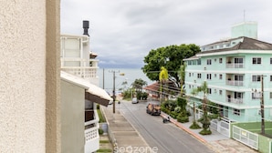 A street view with a building on the left, a green building with balconies on the right, and a clear sky. - Cozy Apartment 6 Minutes From Canas Beach Acg302 (Florianópolis)