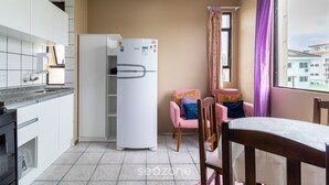 A compact kitchen with a refrigerator, a dining area with a table and chairs, and a window with curtains. - Cozy Apartment 6 Minutes From Canas Beach Acg302 (Florianópolis)