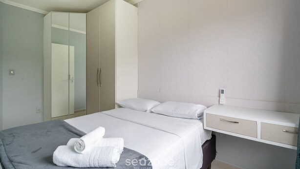 A bedroom with a bed, a bedside table, a wardrobe, and a mirror. - Apartment w/ Barbecue 850m From the Beach Acl0303 (Florianópolis)