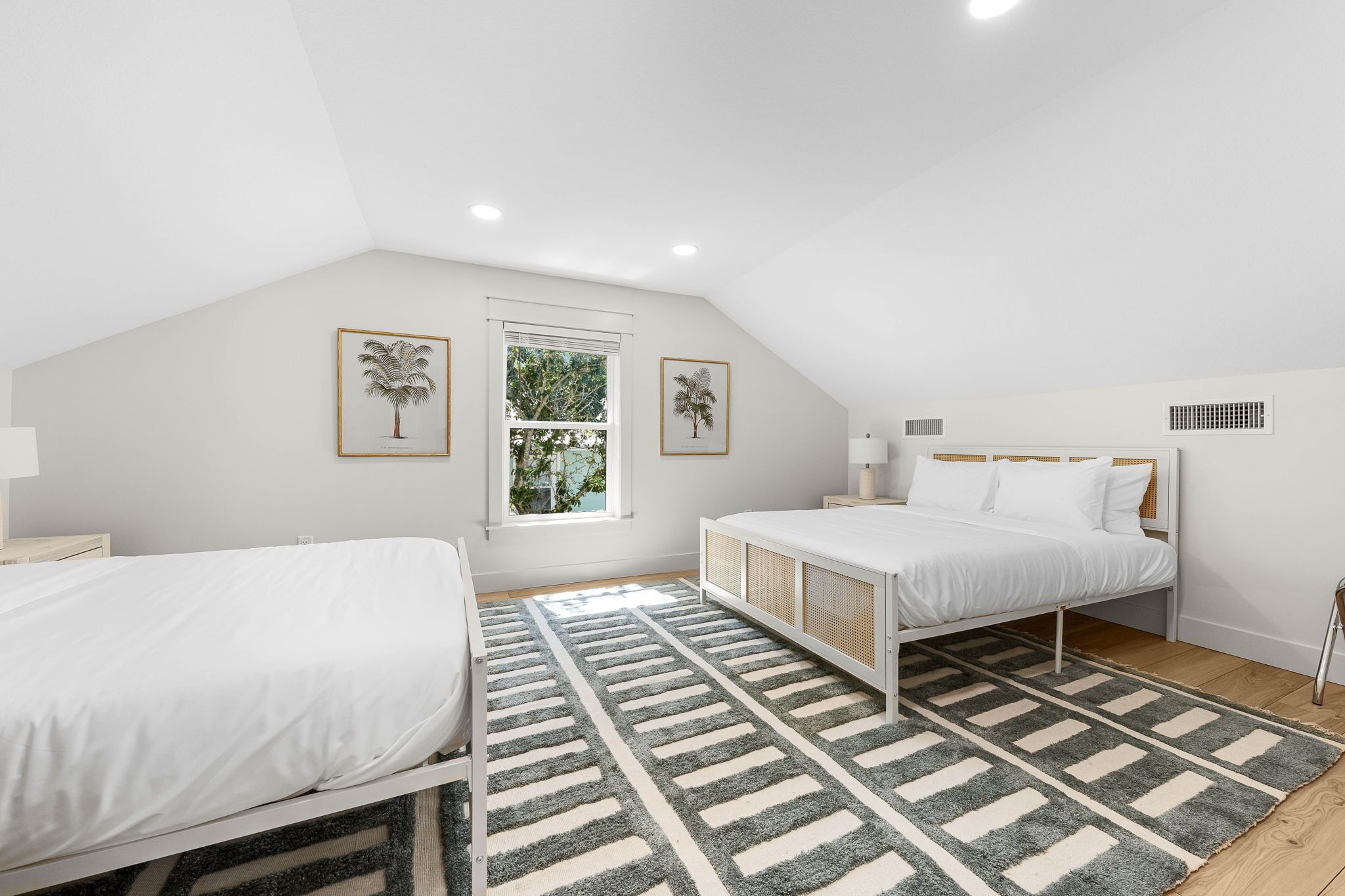 Un dormitorio con dos camas, un ventanal grande y un ventilador de techo.