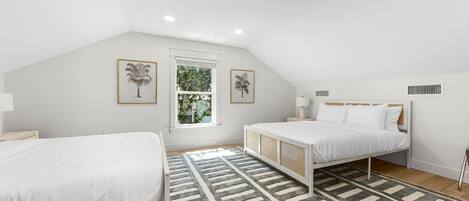 Un dormitorio con dos camas, un ventanal grande y un ventilador de techo.