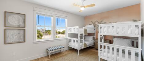 Un dormitorio con literas, una ventana con persianas, un ventilador de techo y vistas al exterior.