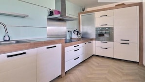 A modern kitchen with a stainless steel sink, white cabinets, a wooden countertop, and a built-in oven.