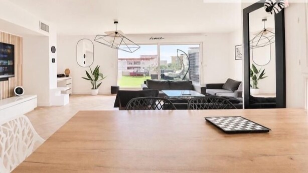 A modern living room with a TV, dining table, and seating area.
