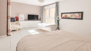 A bedroom with a bed, a TV, a desk, and a window.