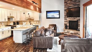 Una cocina moderna con armarios blancos, una isla grande y una chimenea de piedra.