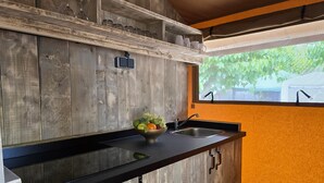 A kitchen with a wooden backsplash, a black countertop, a sink, and a window with a view of greenery.