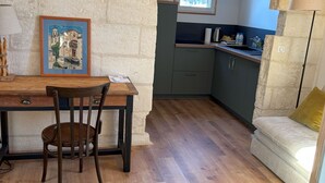 A rustic kitchen with a stone wall, wooden beams, and a window overlooking a cityscape. - Charming apartment in a private mansion in the center of Avignon (Avignon)
