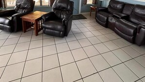 Une pièce spacieuse dotée d’une grande fenêtre, d’une porte et d’un coin salon avec des canapés en cuir et une table en bois.