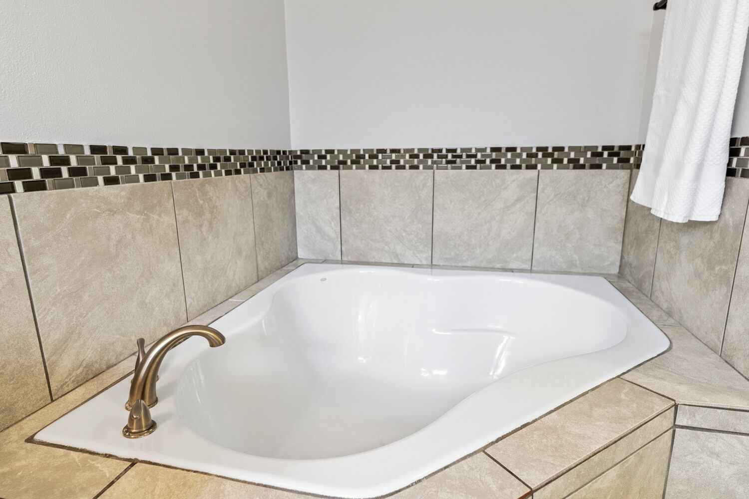 A modern bathroom with a freestanding bathtub, tiled walls, and a white towel hanging on the wall.
