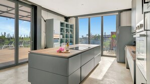 Una cocina moderna con una isla grande, estantes empotrados y una puerta corredera de vidrio que da a una terraza.
