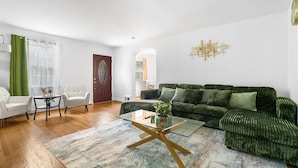 A living room with a green sofa, white armchairs, and a glass coffee table. - Newly active beautiful 5-bedroom house in a prime location near DC (Arlington)