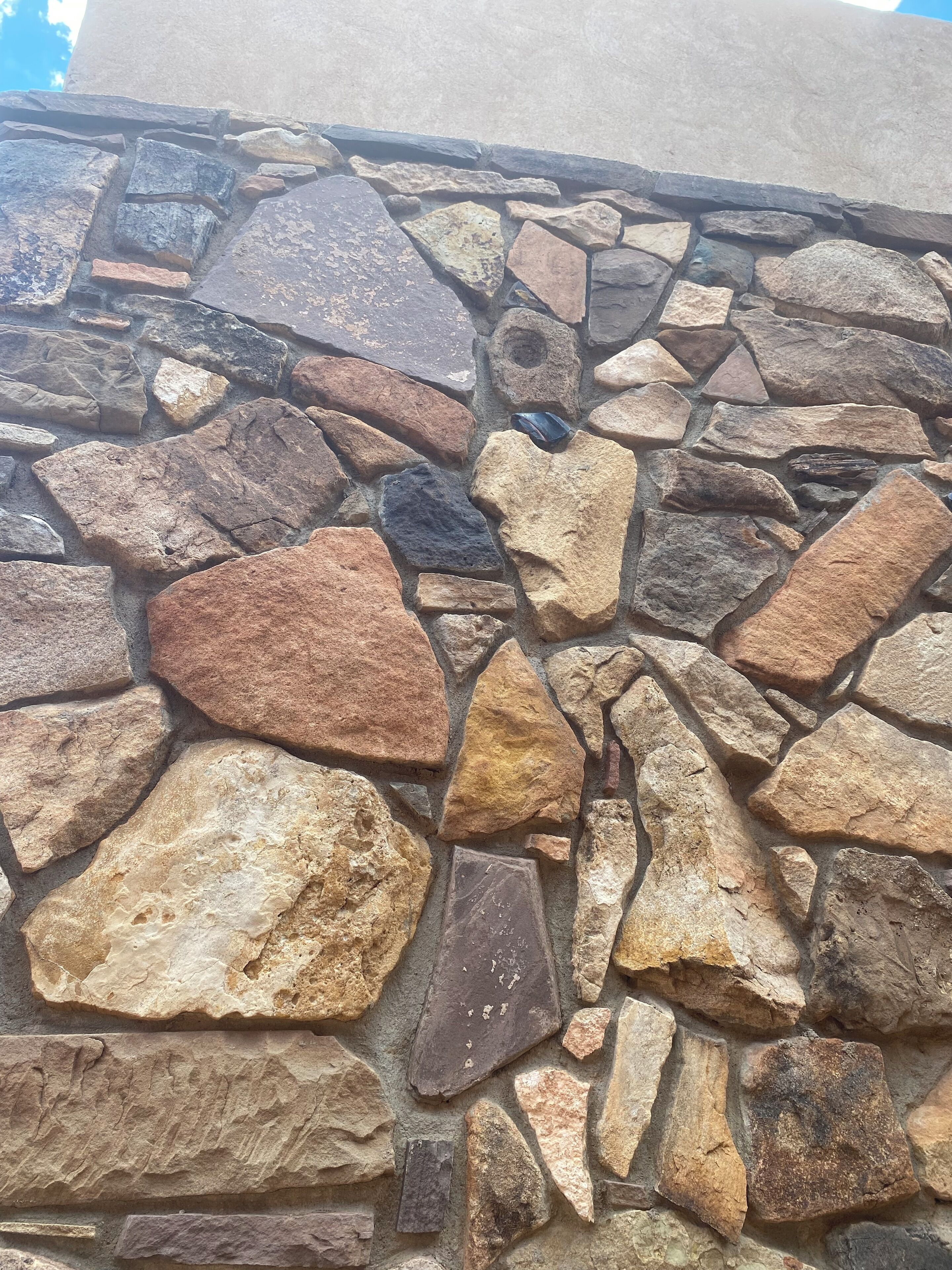 A stone wall with variously shaped and colored stones.