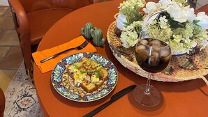 A dining table with a plate of food, a glass of wine, and a decorative basket with flowers.