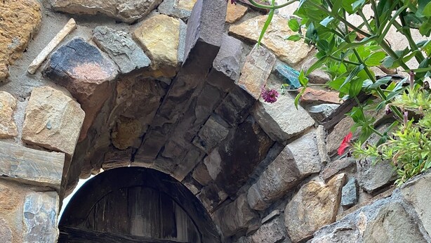 A stone archway leading to a wooden door with a metal handle.