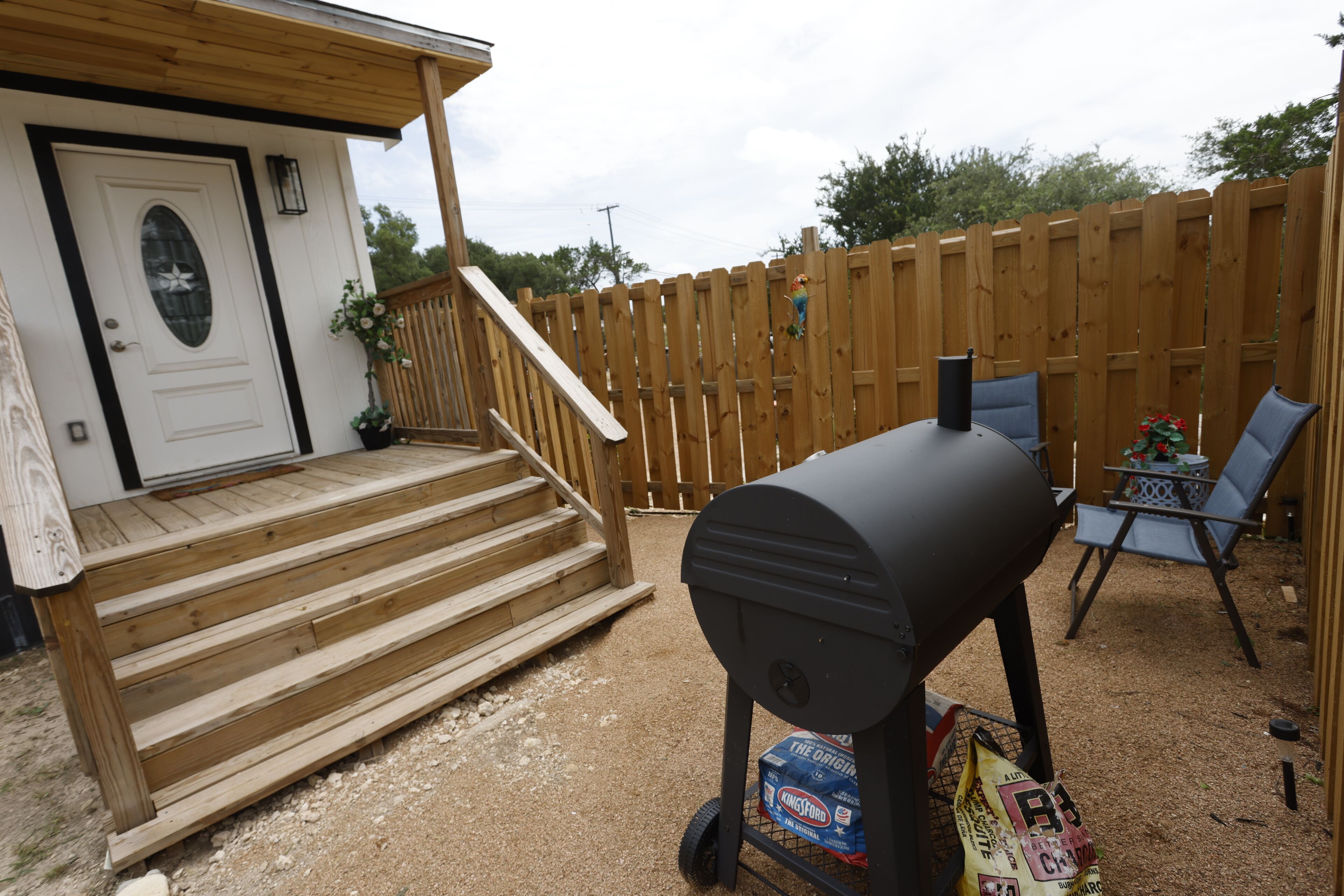 A backyard with a wooden deck, a barbecue grill, and a seating area with chairs.