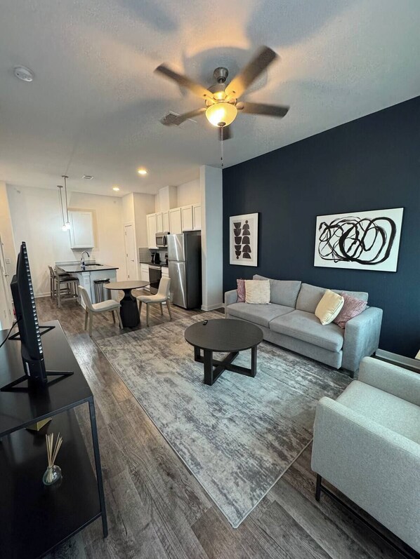 A modern living room with a grey sofa, a coffee table, and a TV on a stand. - Comfy Get Away in Austin (Leander)