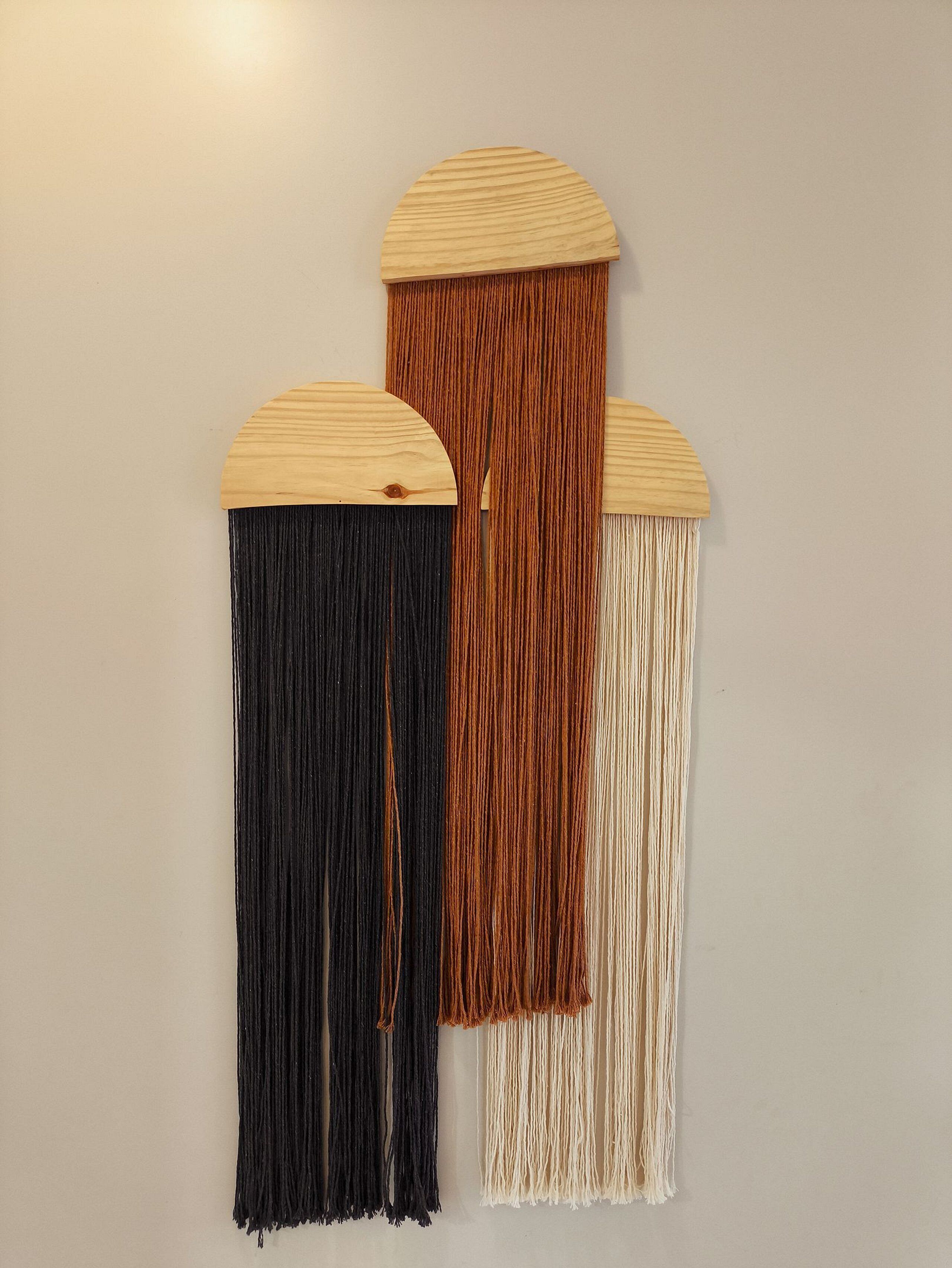 Tres flecos montados en la pared, en colores negro, marrón y blanco.