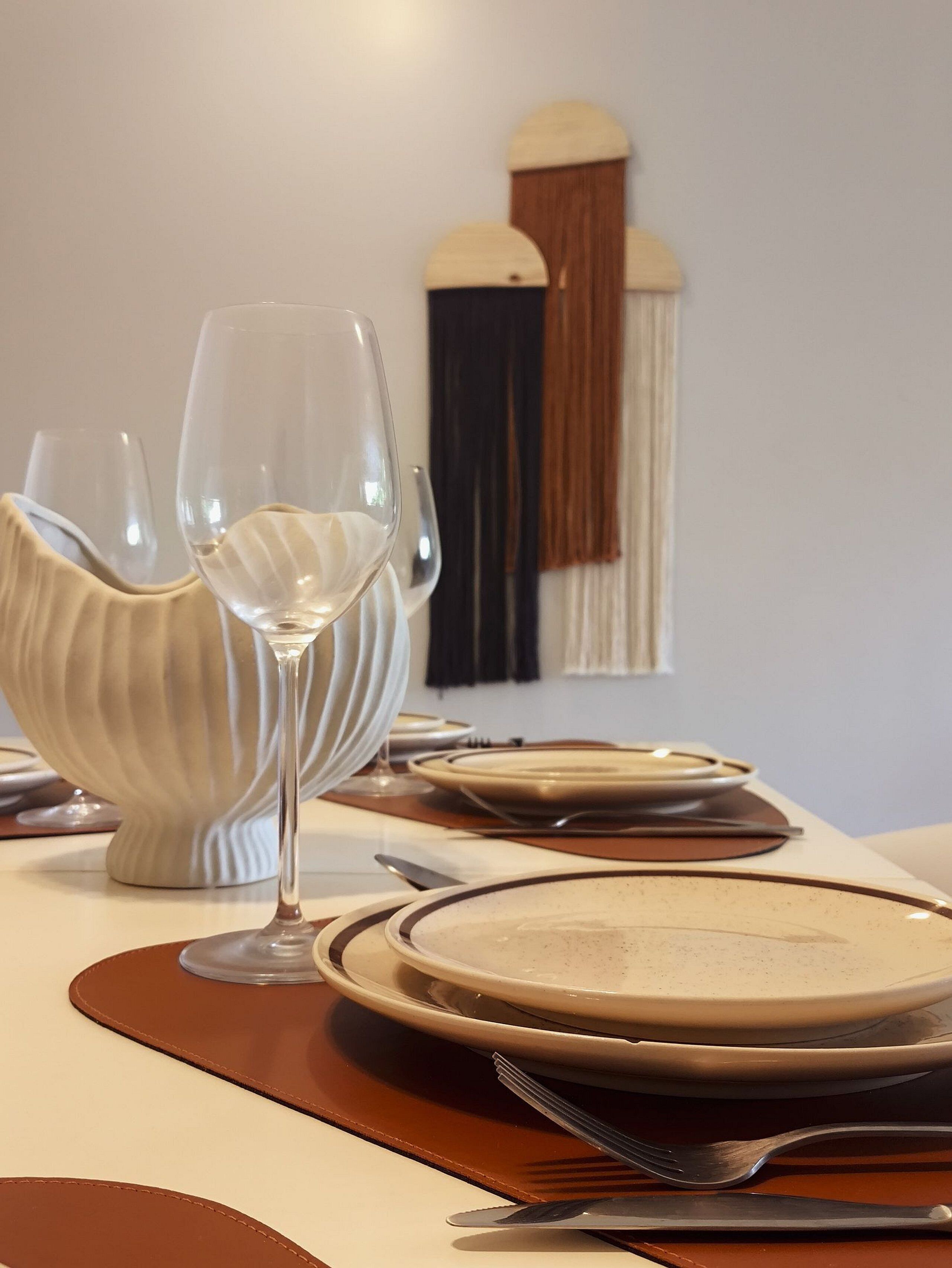 A dining table set with plates, cutlery, and a wine glass.