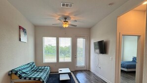A spacious living room with a wooden floor, a sofa, a coffee table, and a ceiling fan. - Pleasant apartment in Austin (Leander)