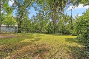 A grassy yard with trees and a small building.